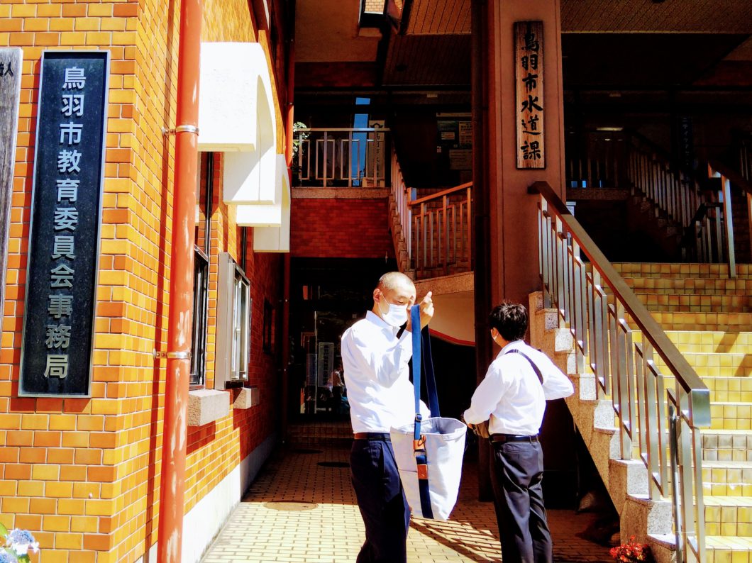 鳥羽市教育委員会の入口に立つ会員