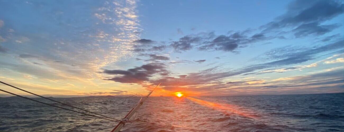 竿の先の水平線からのぼる朝日