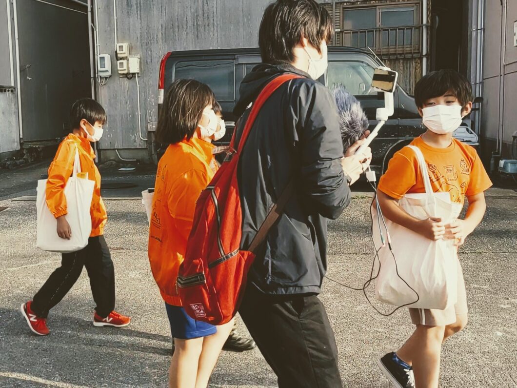 歩きながらタブレット越しに会話をする島っ子ガイド児童