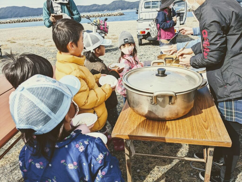 お皿にカレーをよそってもらう子どもたち