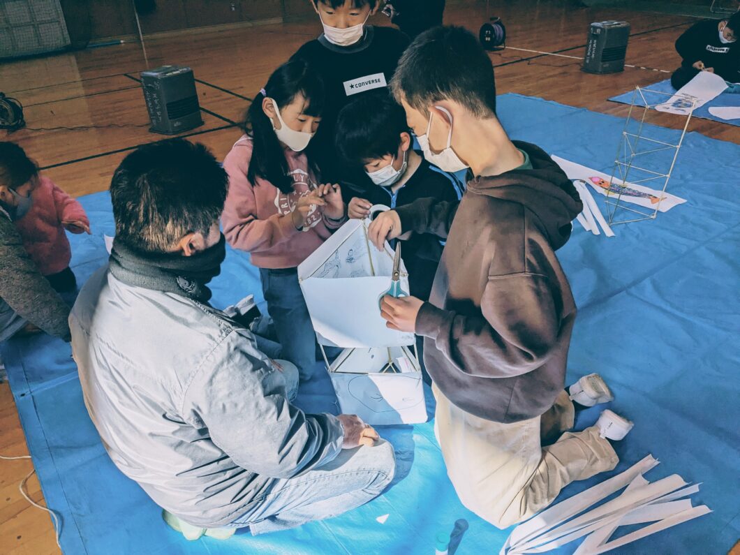 竹ひごの骨組みに障子紙を張る子どもたち